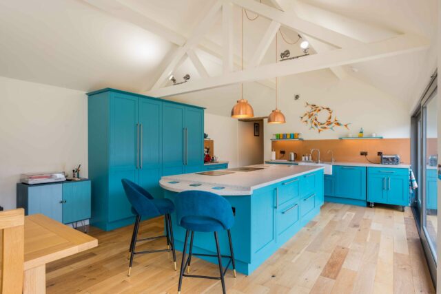 Bespoke shaker kitchen with bold teal cabinets and island stools